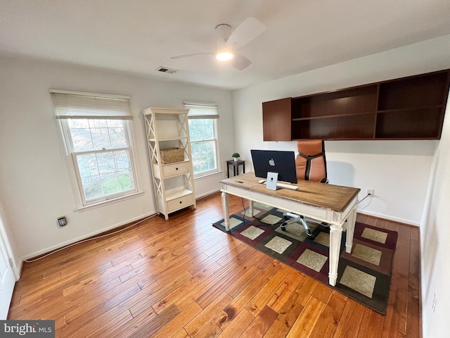 office with baseboards, visible vents, a ceiling fan, and light wood-style floors