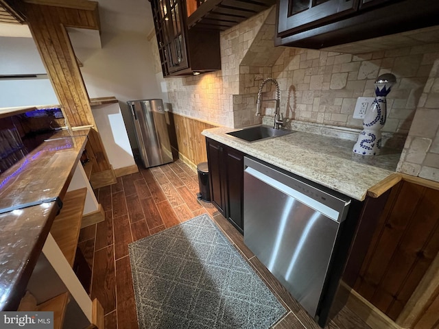 kitchen featuring wood tiled floor, a sink, glass insert cabinets, stainless steel dishwasher, and tasteful backsplash