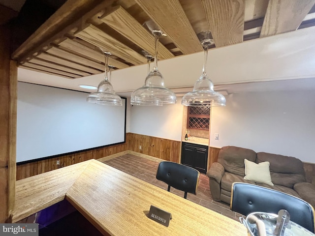 interior space featuring a wainscoted wall, wood walls, and a dry bar