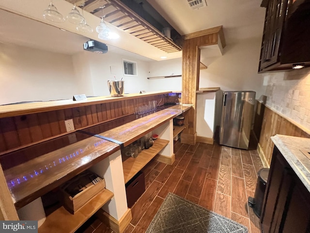 bar with hanging light fixtures and wood finish floors