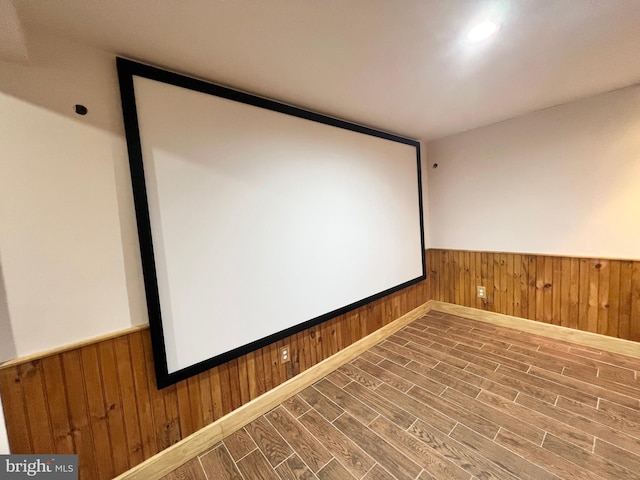 cinema room with wood finished floors, wood walls, and wainscoting