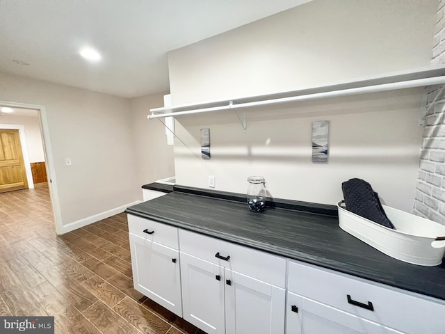 kitchen featuring dark countertops, dark wood finished floors, white cabinetry, recessed lighting, and baseboards