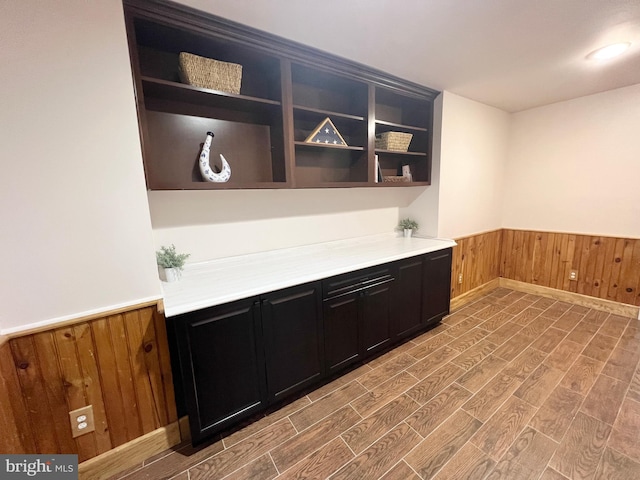 bar with a wainscoted wall, wood walls, and wood finish floors