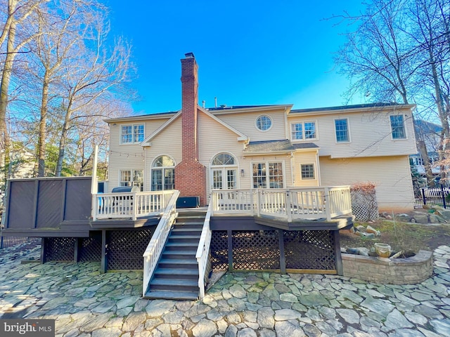 back of house featuring a deck, stairs, and a chimney