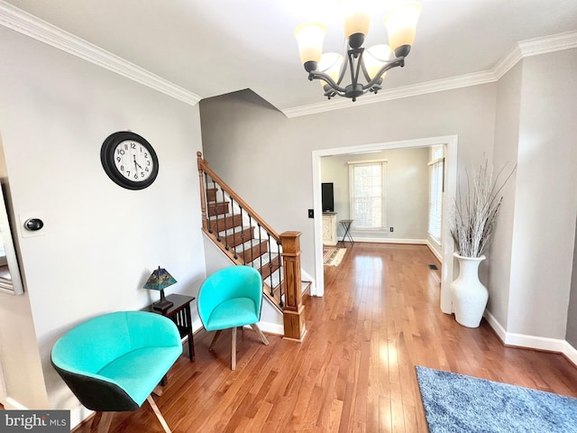 entrance foyer featuring light wood-type flooring, an inviting chandelier, ornamental molding, and stairs