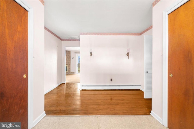 hallway with light hardwood / wood-style flooring, ornamental molding, and a baseboard heating unit