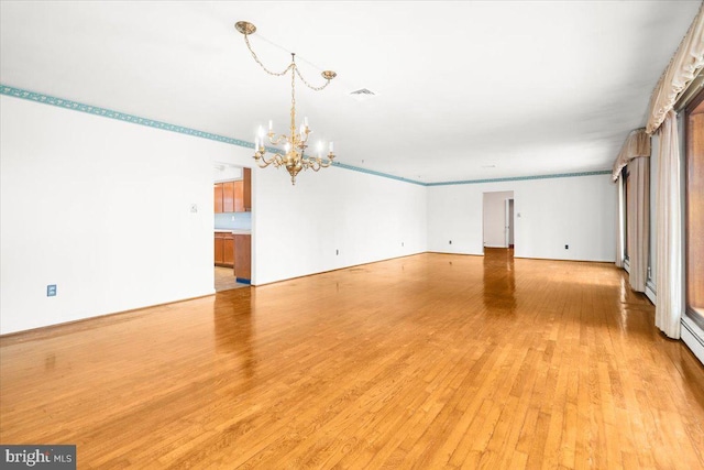 empty room featuring a chandelier, light hardwood / wood-style floors, and ornamental molding