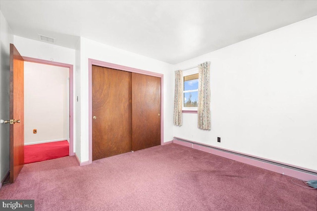 unfurnished bedroom featuring light colored carpet, baseboard heating, and a closet