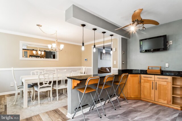 kitchen featuring a kitchen breakfast bar, kitchen peninsula, pendant lighting, wood-type flooring, and ceiling fan with notable chandelier