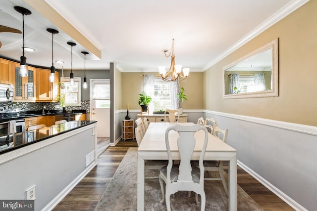 dining room with ornamental molding, dark wood-type flooring, and an inviting chandelier