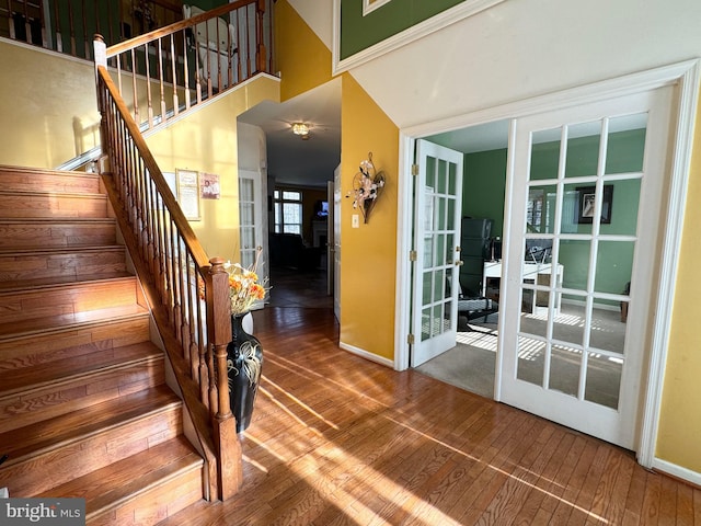 stairway featuring wood-type flooring, a high ceiling, and french doors