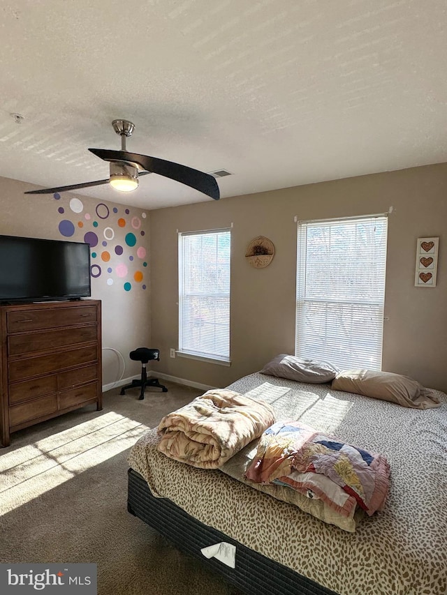 carpeted bedroom featuring multiple windows, ceiling fan, and a textured ceiling