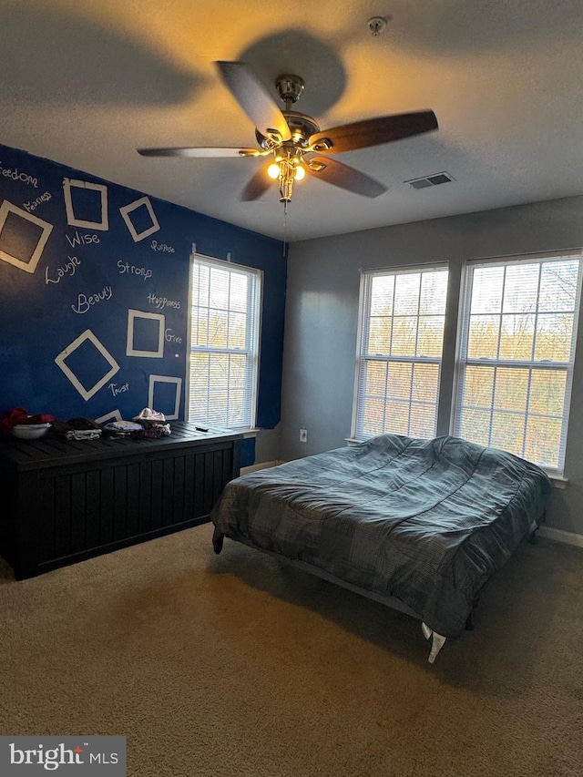 carpeted bedroom featuring multiple windows and ceiling fan