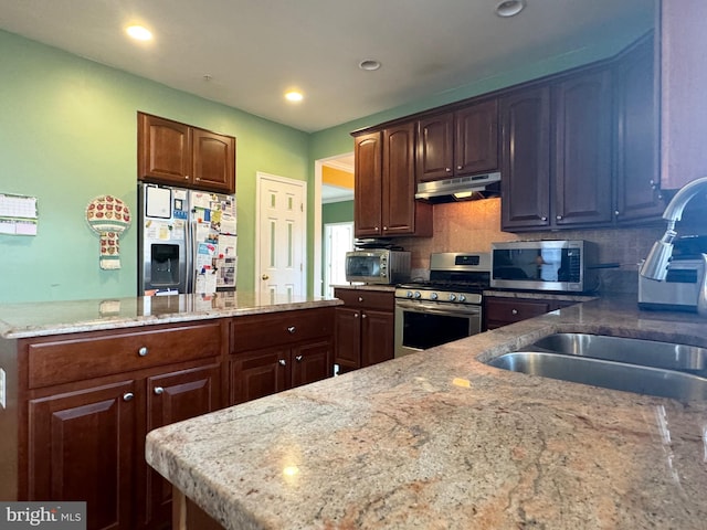 kitchen featuring light stone countertops, backsplash, stainless steel appliances, and sink