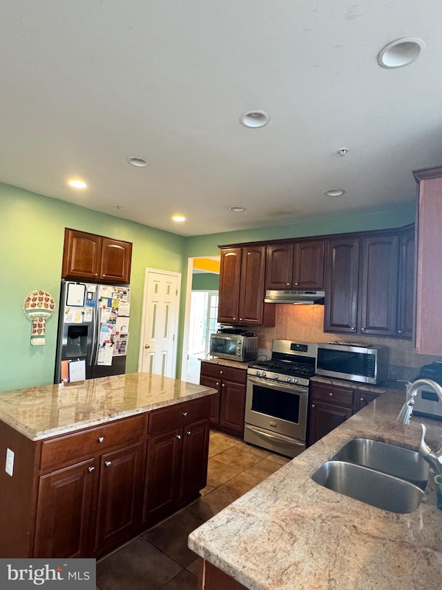 kitchen with light stone countertops, appliances with stainless steel finishes, tasteful backsplash, sink, and light tile patterned flooring