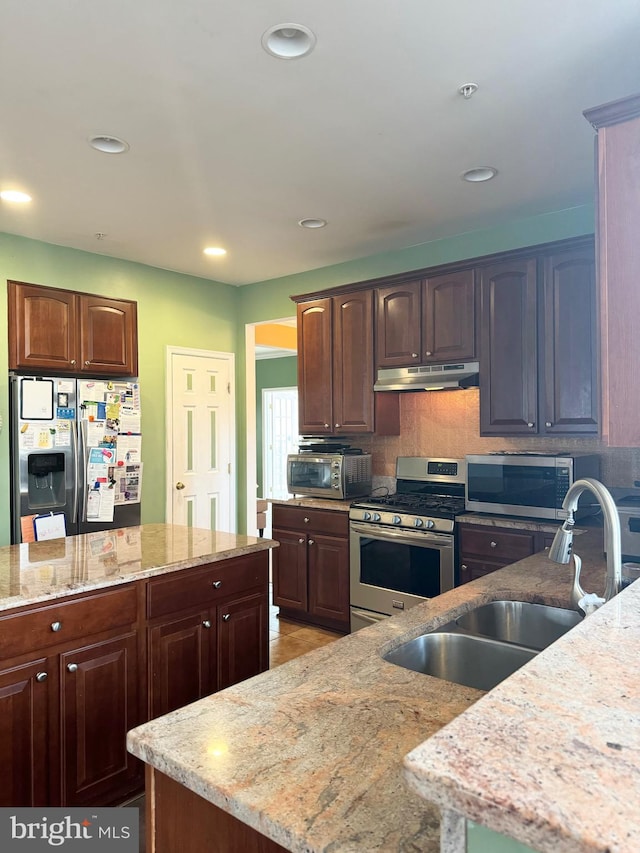 kitchen with light stone countertops, sink, a center island, and appliances with stainless steel finishes