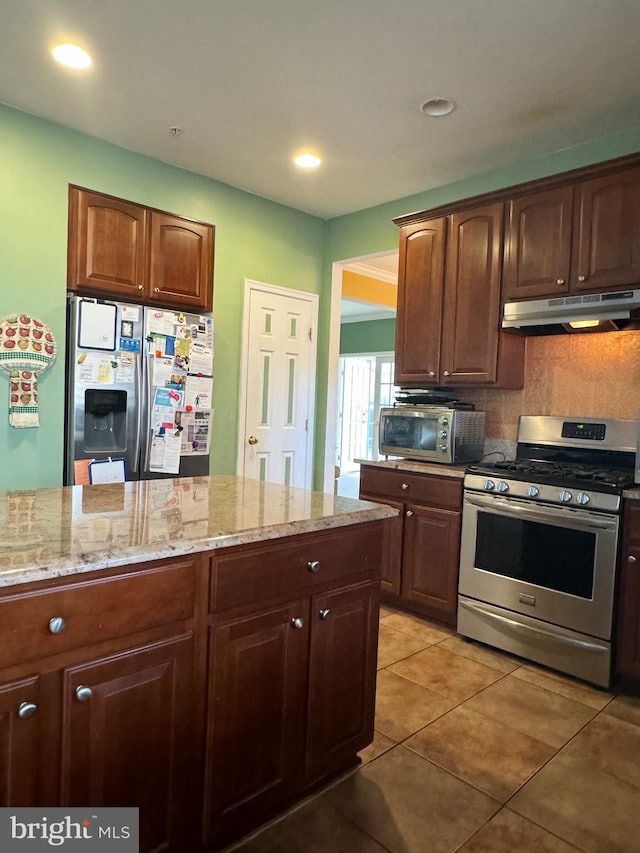 kitchen with decorative backsplash, light tile patterned flooring, light stone counters, and appliances with stainless steel finishes