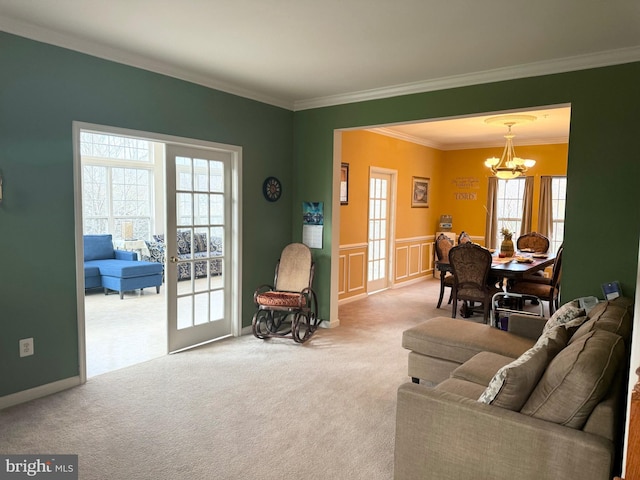 carpeted living room with french doors, an inviting chandelier, and ornamental molding