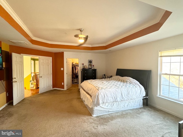 bedroom with carpet flooring, a walk in closet, a raised ceiling, and a closet