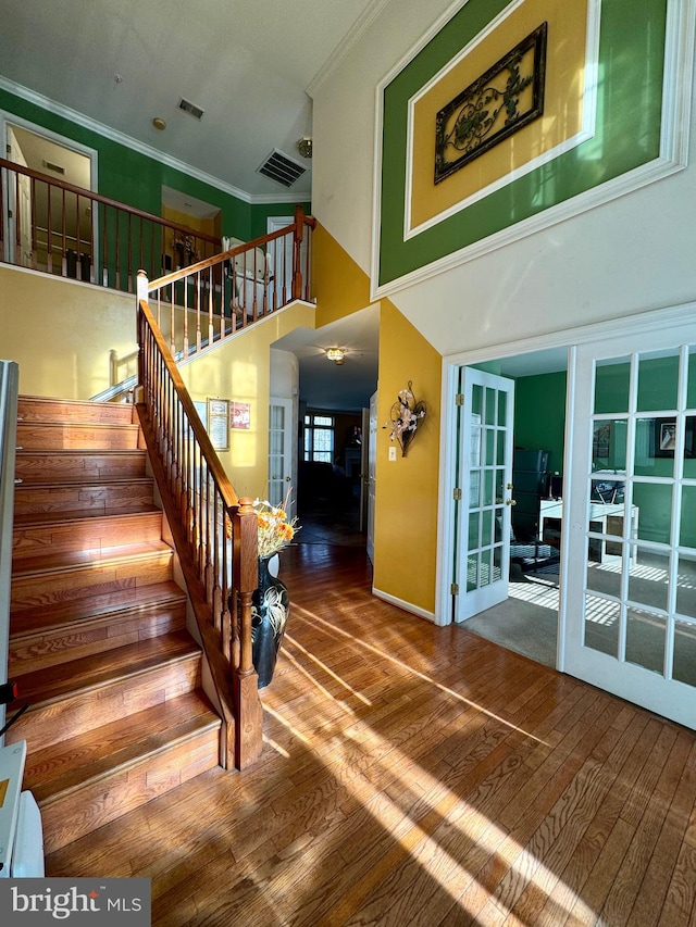 stairway featuring crown molding, hardwood / wood-style floors, and a high ceiling