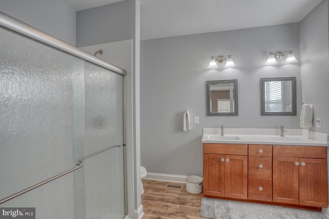 bathroom featuring vanity, hardwood / wood-style flooring, toilet, and an enclosed shower