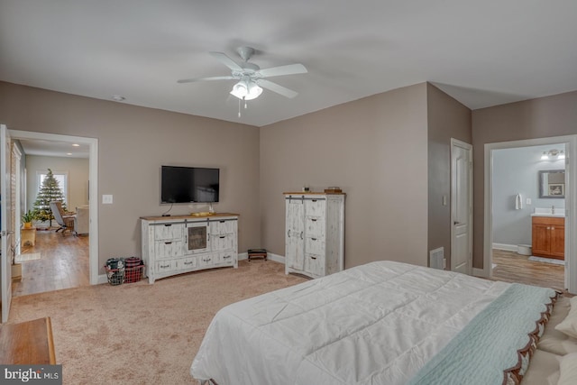 bedroom featuring sink, light wood-type flooring, ceiling fan, and connected bathroom