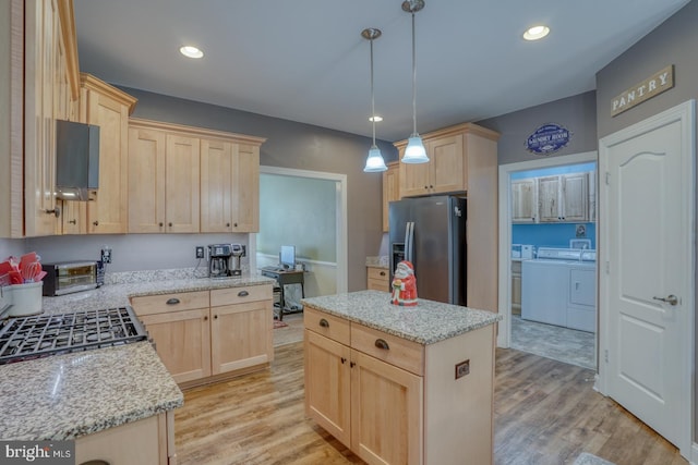 kitchen featuring washer and clothes dryer, pendant lighting, light wood-type flooring, and appliances with stainless steel finishes