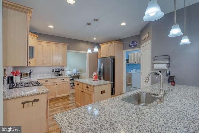 kitchen featuring a center island, sink, hanging light fixtures, separate washer and dryer, and light brown cabinetry