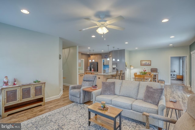 living room featuring light hardwood / wood-style flooring, ceiling fan, and sink