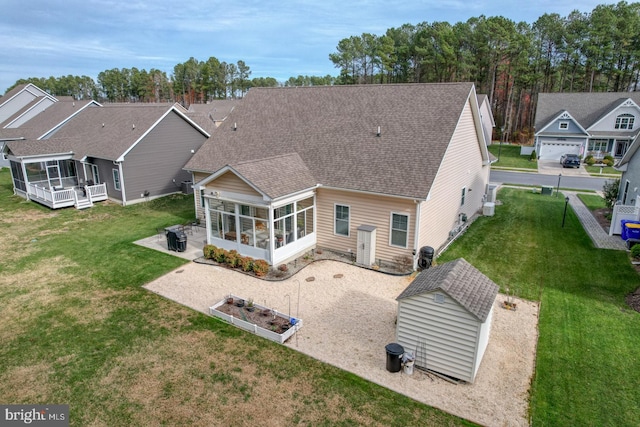 back of house with a sunroom, a storage unit, a patio area, and a yard