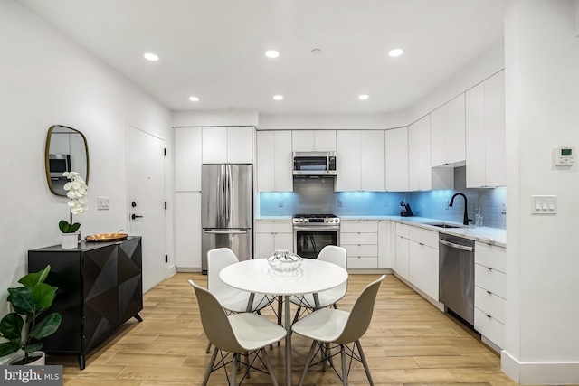 kitchen featuring white cabinetry, sink, stainless steel appliances, and light hardwood / wood-style flooring