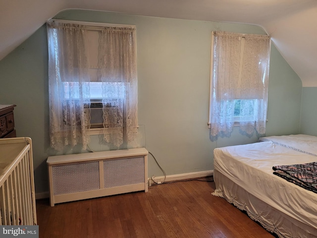 bedroom with hardwood / wood-style floors, lofted ceiling, cooling unit, and radiator heating unit