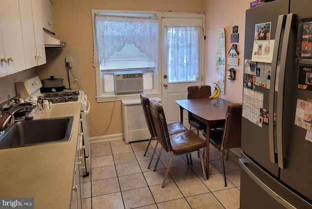 dining space featuring cooling unit, sink, light tile patterned floors, and radiator heating unit