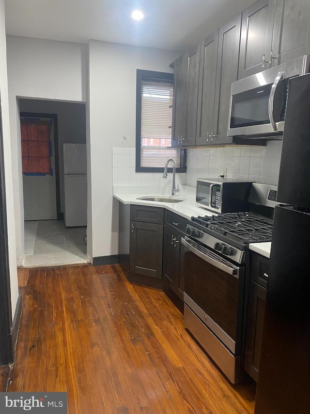 kitchen with decorative backsplash, dark hardwood / wood-style flooring, stainless steel appliances, and sink