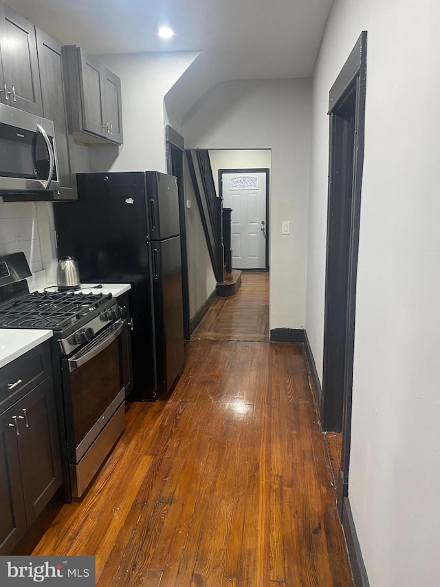 kitchen with backsplash, dark wood-type flooring, and appliances with stainless steel finishes