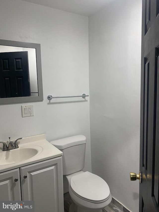 bathroom with hardwood / wood-style floors, vanity, and toilet