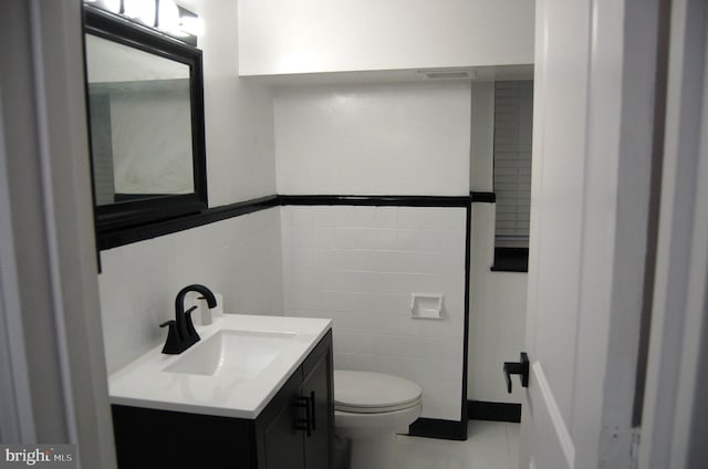 bathroom with tile patterned floors, vanity, tile walls, and toilet