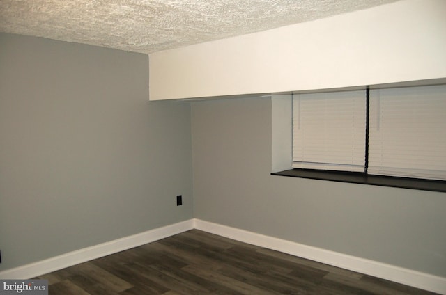 unfurnished room with a textured ceiling and dark wood-type flooring