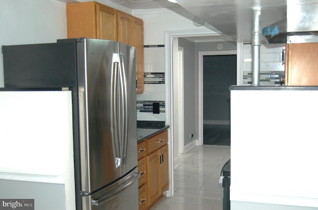 kitchen featuring decorative backsplash, light tile patterned floors, and stainless steel refrigerator