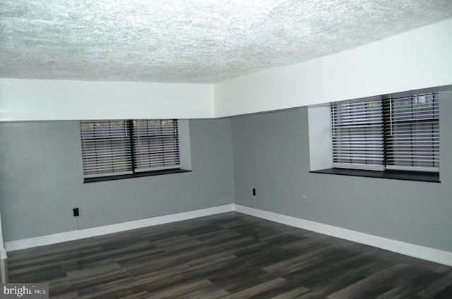 empty room with a textured ceiling and dark wood-type flooring