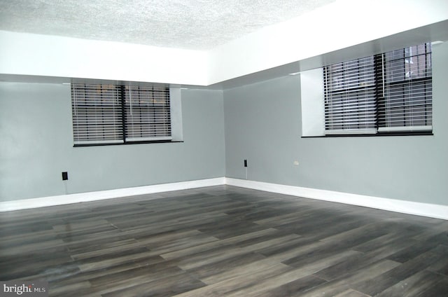 spare room featuring a textured ceiling and dark hardwood / wood-style flooring