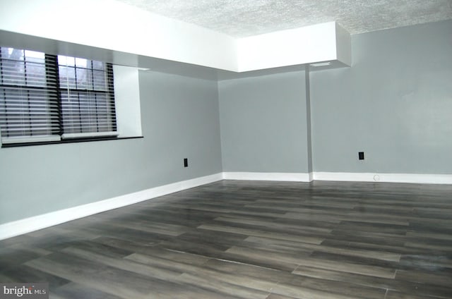 empty room with dark wood-type flooring and a textured ceiling