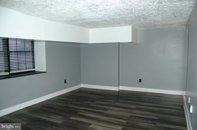 empty room featuring a textured ceiling and dark wood-type flooring