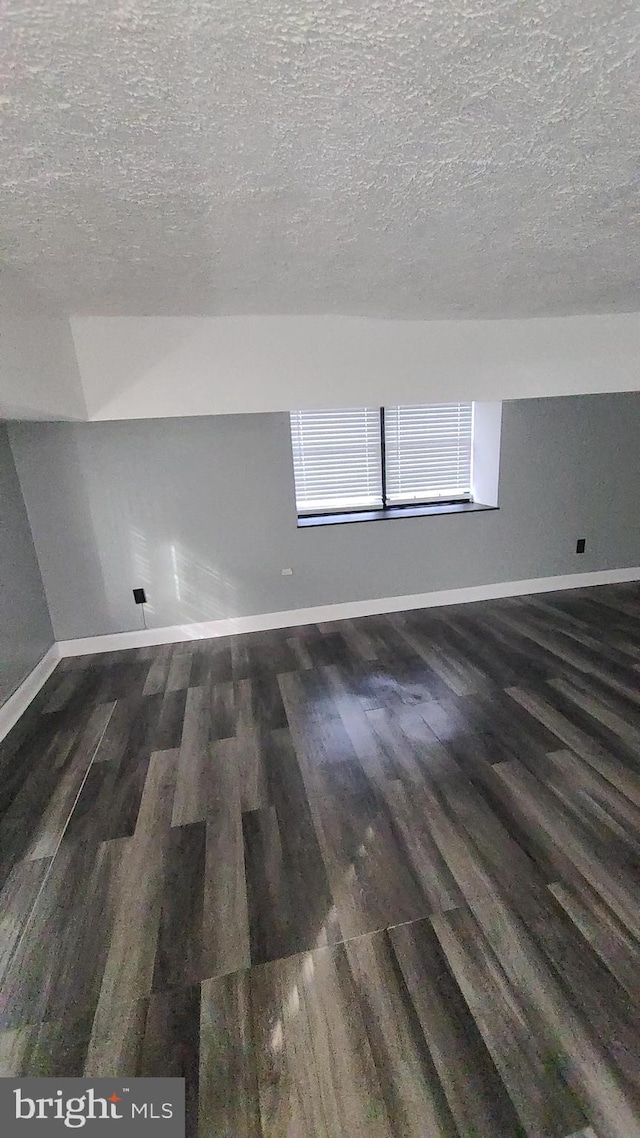 bonus room featuring dark wood-type flooring and a textured ceiling