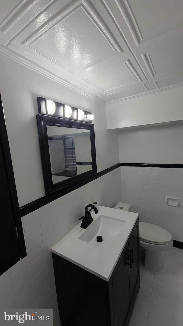 bathroom featuring tile patterned floors, vanity, toilet, and tile walls