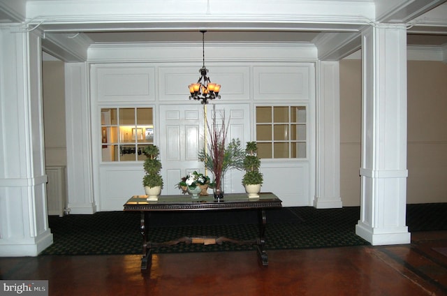 interior space featuring ornate columns, crown molding, and a chandelier