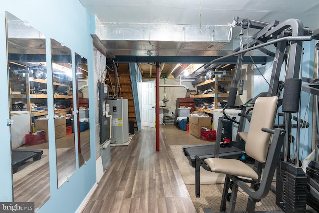 basement featuring washer / clothes dryer, electric water heater, and wood-type flooring