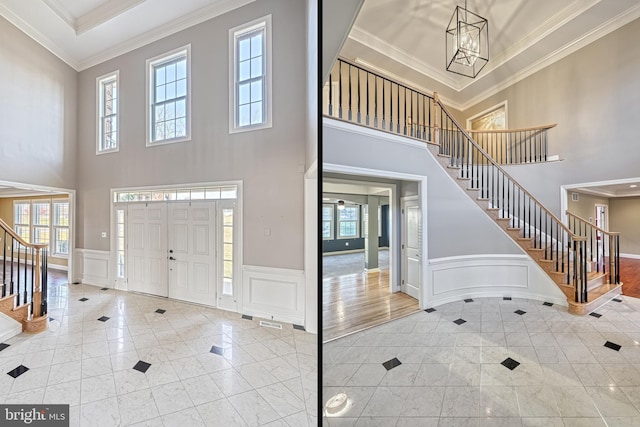 foyer with light hardwood / wood-style floors, a towering ceiling, ornamental molding, and an inviting chandelier