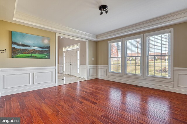 unfurnished room with hardwood / wood-style floors, a tray ceiling, and ornamental molding