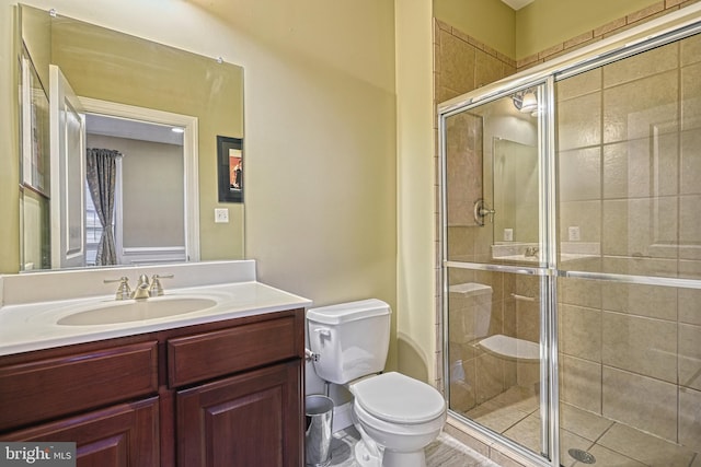 bathroom featuring vanity, toilet, and a shower with shower door